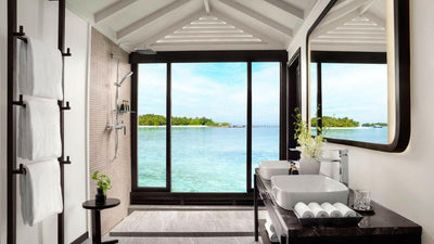 A Superior Over Water Villa bathroom at Anantara Veli, walk-in shower and twin basins by the window