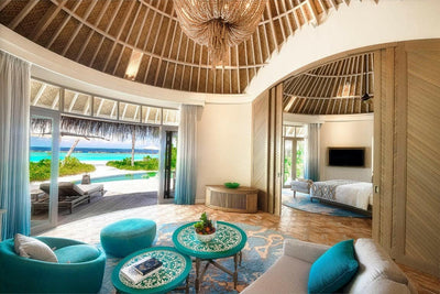 The living area of a Beach House at The Nautilus Maldives, teal seating under a high thatched ceiling