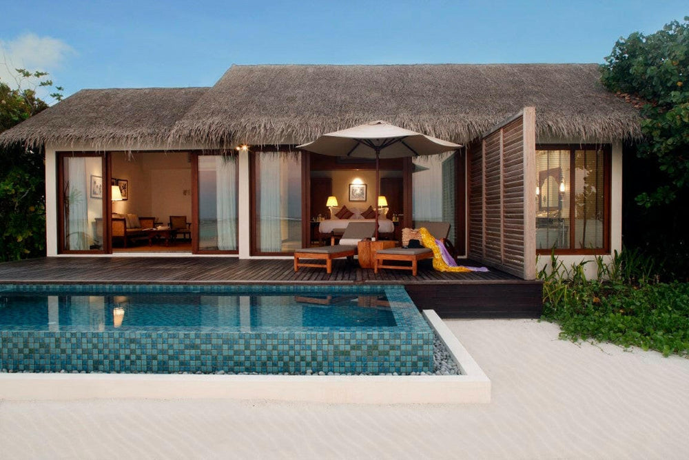 A Beach Pool Villa at The Residence Maldives at Falhumaafushi, lit at dusk behind its private pool
