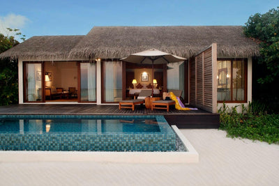A Beach Pool Villa at The Residence Maldives at Falhumaafushi, lit at dusk behind its private pool