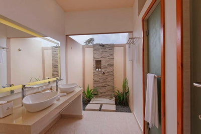 A Beach Villa bathroom at Brennia Kottefaru, twin basins and a stone walled walk-in shower