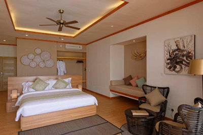 A Beach Villa bedroom at Brennia Kottefaru, seating at the foot of the bed under a high ceiling