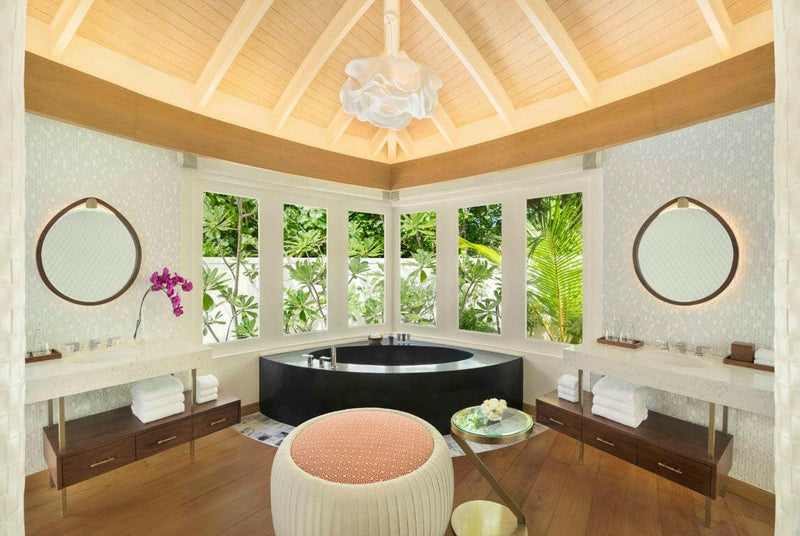 A beach villa bathroom at JW Marriott Maldives, twin vanities, a dark tub and louvres onto the garden.