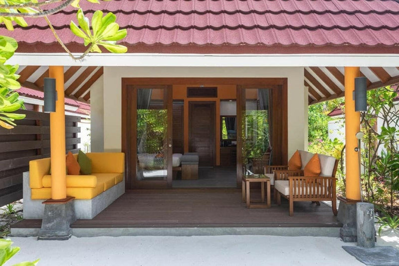 A beach villa veranda at Dhigufaru Island Resort, yellow bench seat under a red tiled roof.