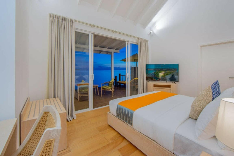 A villa bedroom at Dhigufaru Island Resort, a whale shark painting above a bench, sea light outside.