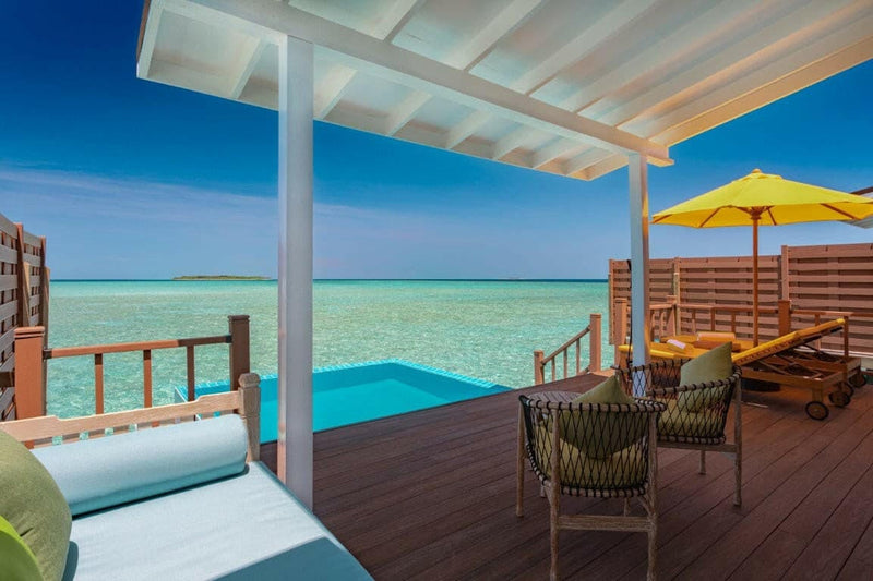 A water villa deck at Dhigufaru Island Resort, plunge pool in the timber beside a blue daybed.
