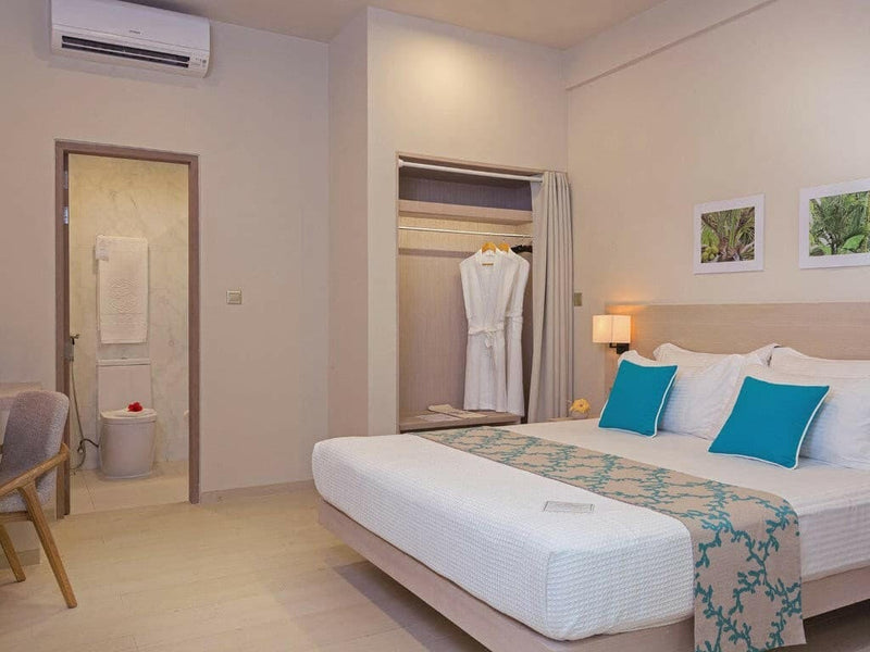 A Garden Room at Malahini Kuda Bandos with a king bed, an open wardrobe holding robes and the ensuite doorway beyond.
