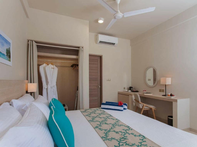 A Superior Room at Malahini Kuda Bandos with a ceiling fan, writing desk and chair beside the bed.