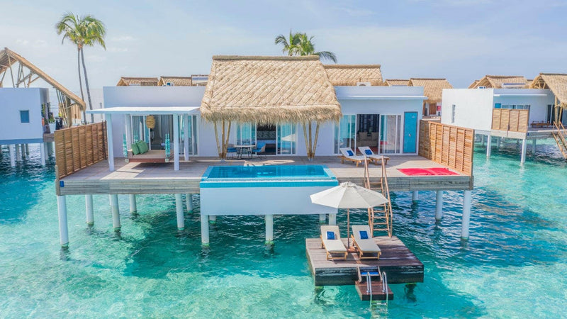 Water villas at Emerald Maldives, thatched roofs and deck pools above a bright turquoise lagoon.