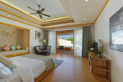 A Deluxe Beach Pool Villa bedroom at Brennia Kottefaru, doors folded back onto the garden