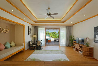 A Deluxe Beach Pool Villa at Brennia Kottefaru, the bed facing a seating area and the terrace