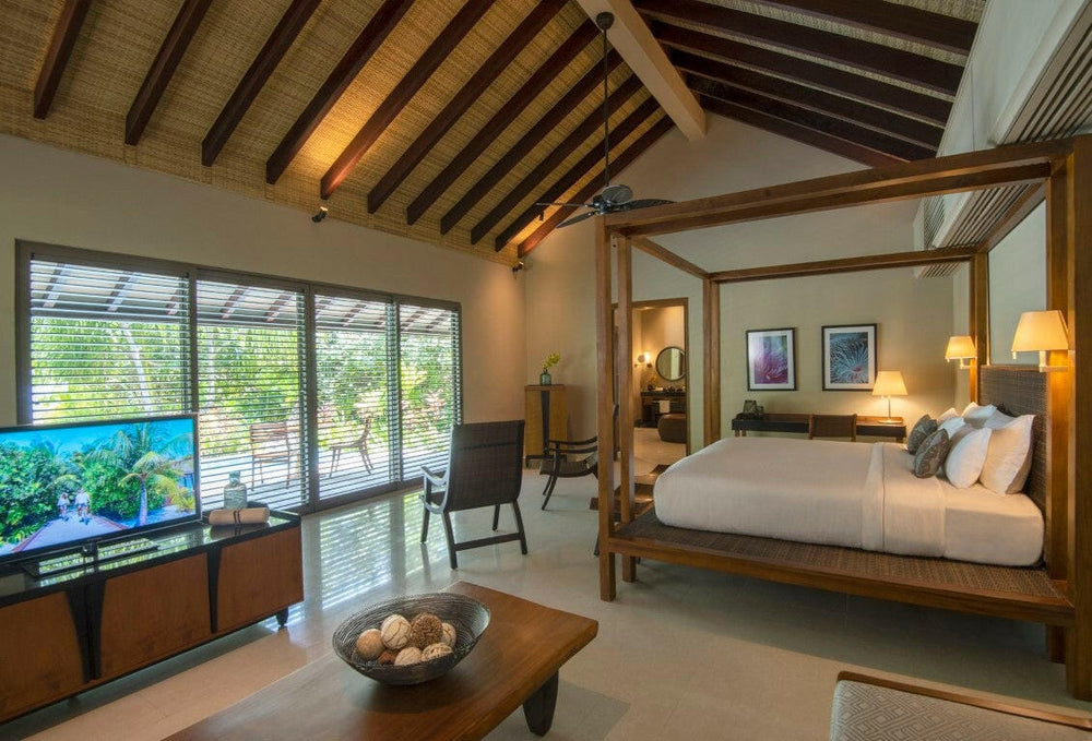 A Deluxe Beach Pool Villa bedroom at The Residence Maldives at Dhigurah, under a timber ceiling with doors to the garden