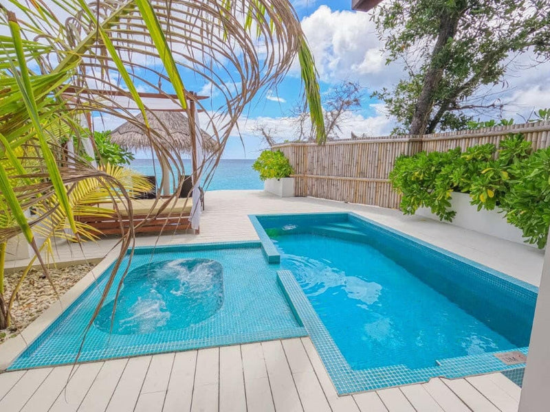 A private pool at Malahini Kuda Bandos with a separate plunge section on a wooden deck, screened by a bamboo fence with the sea beyond.