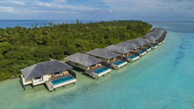 Lagoon villas at The Residence Maldives at Dhigurah from the air, a line of thatched villas along a curving jetty