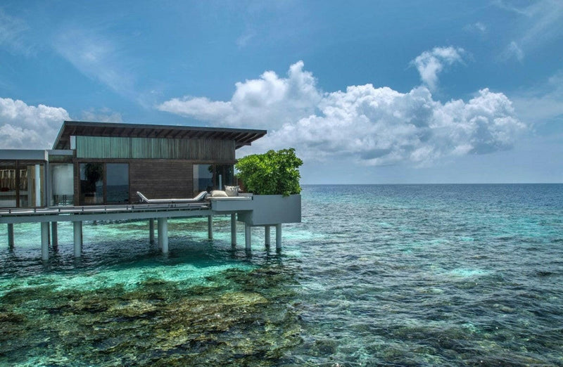 An overwater villa at Park Hyatt Maldives Hadahaa on stilts above the reef, seen from the lagoon