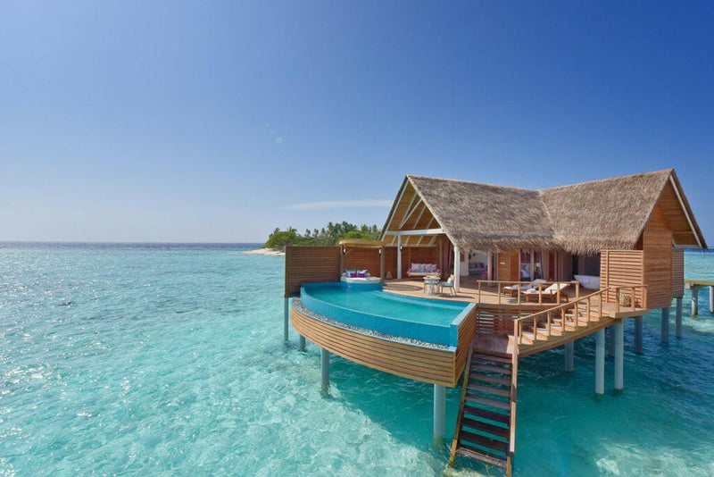 A Water Pool Villa at Milaidhoo Maldives, curved blue pool on the deck above turquoise shallows.