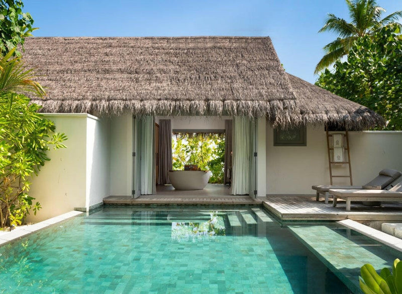 A private pool at Vakkaru Maldives, turquoise tiles running up to a thatched pavilion among palms.