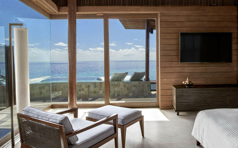 Looking out from an Over Water Sunset Pool Villa at Park Hyatt Maldives Hadahaa, loungers on the deck and open sea beyond the glass