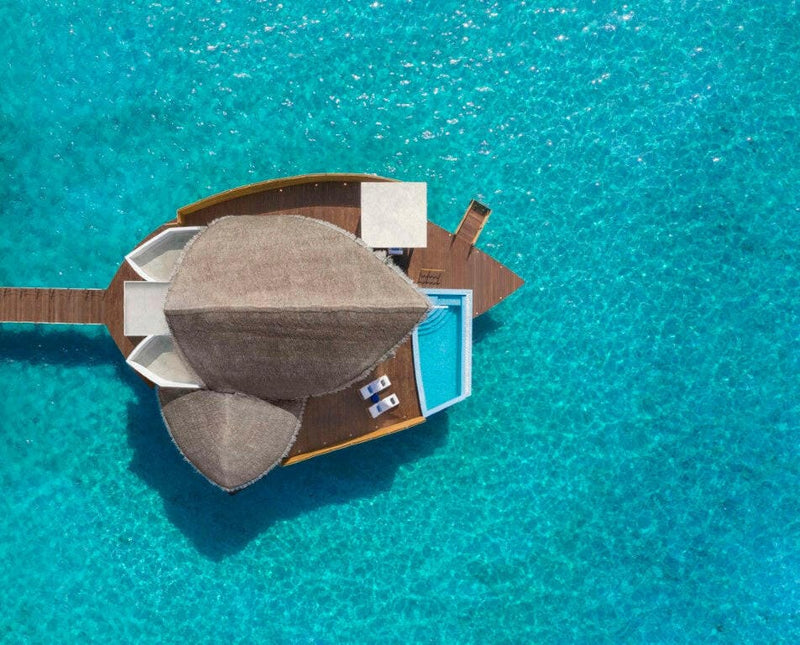 An overwater villa at JW Marriott Maldives seen from above, plunge pool and jetty over turquoise water.