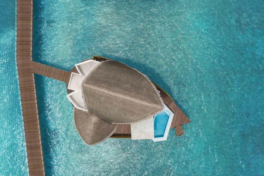 JW Marriott Maldives from directly above, a shell shaped overwater villa and its pale blue plunge pool.
