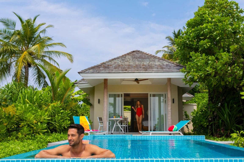 A guest swimming in a villa pool at Kandima Maldives, another standing in the doorway behind.