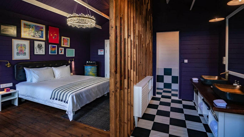 A Veyoge Gallery Pool Villa bedroom at Oaga Art Resort, framed pictures covering a deep plum wall above a chequered floor