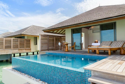 A water pool villa at The Residence Maldives at Dhigurah, a long private pool and loungers on the deck