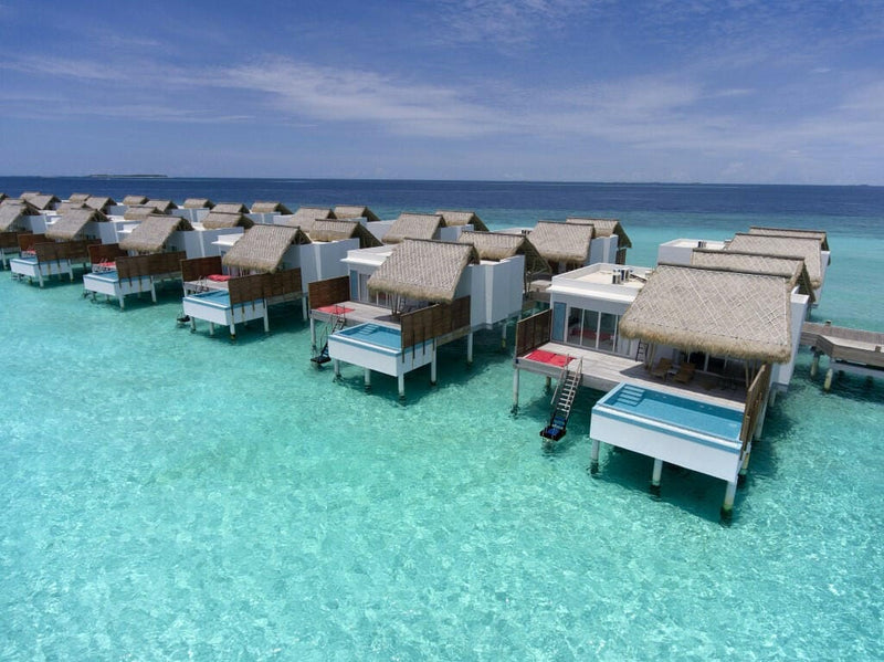 Water villas at Emerald Maldives, red cushioned loungers and steps down into the calm lagoon.